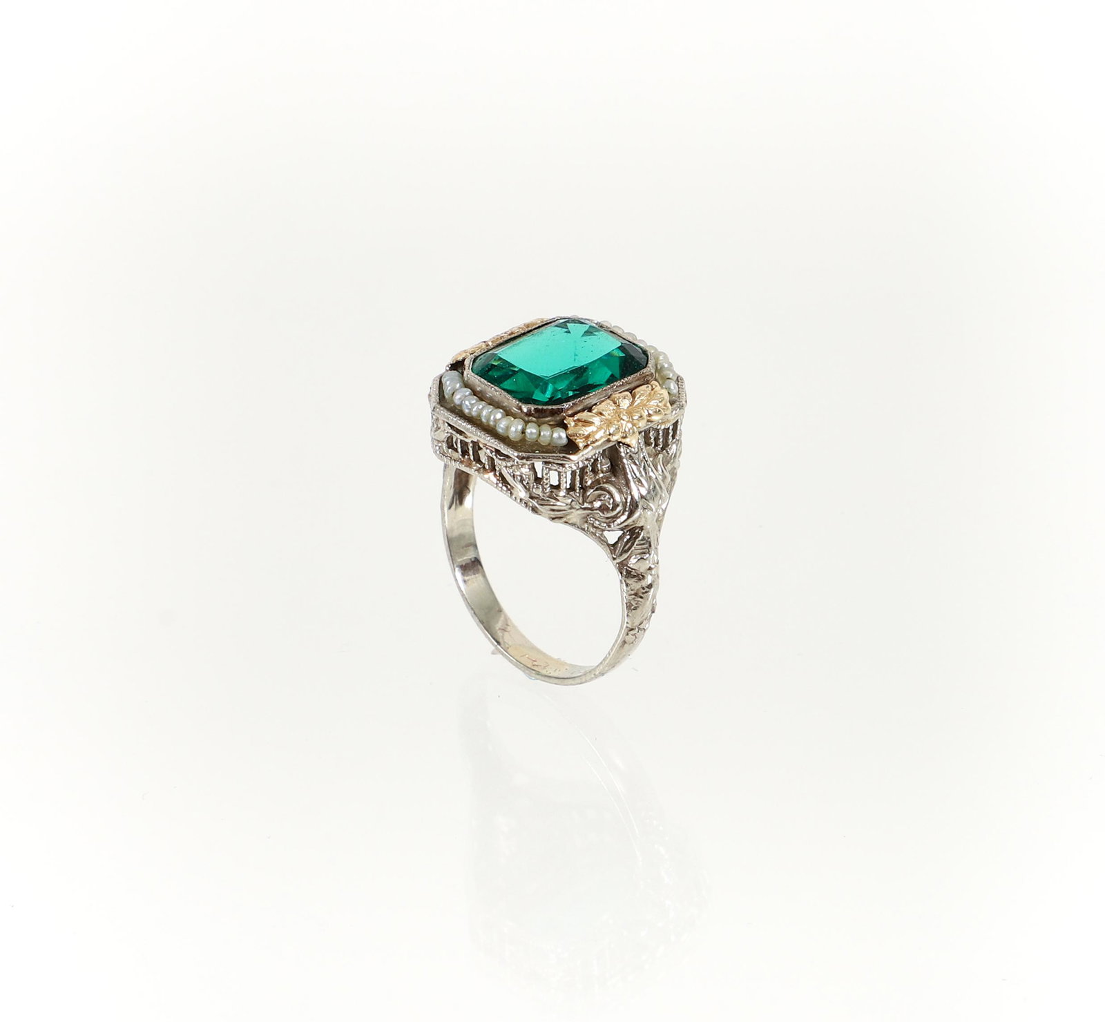14K Green Spinel Pearl Ring: 14K bi-color synthetic green spinel and seed pearl ring. The emerald cut spinel is set in a slightly raised yellow gold bezel and surrounded by yellow gold cutwork flowers and seed pearls. The intrica