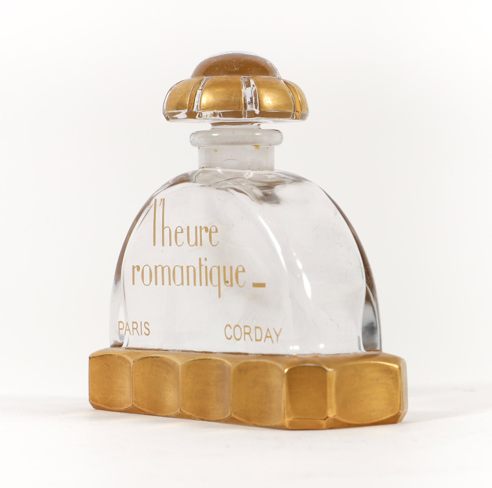 Baccarat for Corday L'heure Romantique Perfume Bottle: A 1930s Baccarat for Corday L'Heure Romantique (Romantic Hour) clear crystal perfume bottle and stopper, gilt labeling and detail, Baccarat mark incised at underside. 3.25 x 3.25 x 1.25 inches.