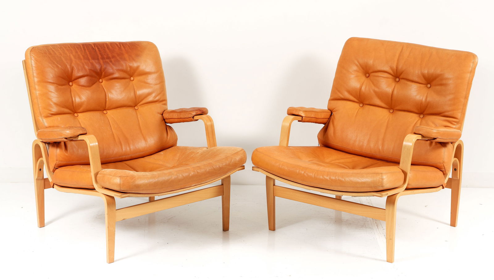 A Pair of Bruno Mathsson for Dux Ingrid Lounge Chairs: A pair of Bruno Mathsson for Dux Ingrid lounge chairs, laminated bent beechwood frames with buttery tufted russet leather seats and back cushions. Both with Bruno Mathsson for Dux wood burned into rea