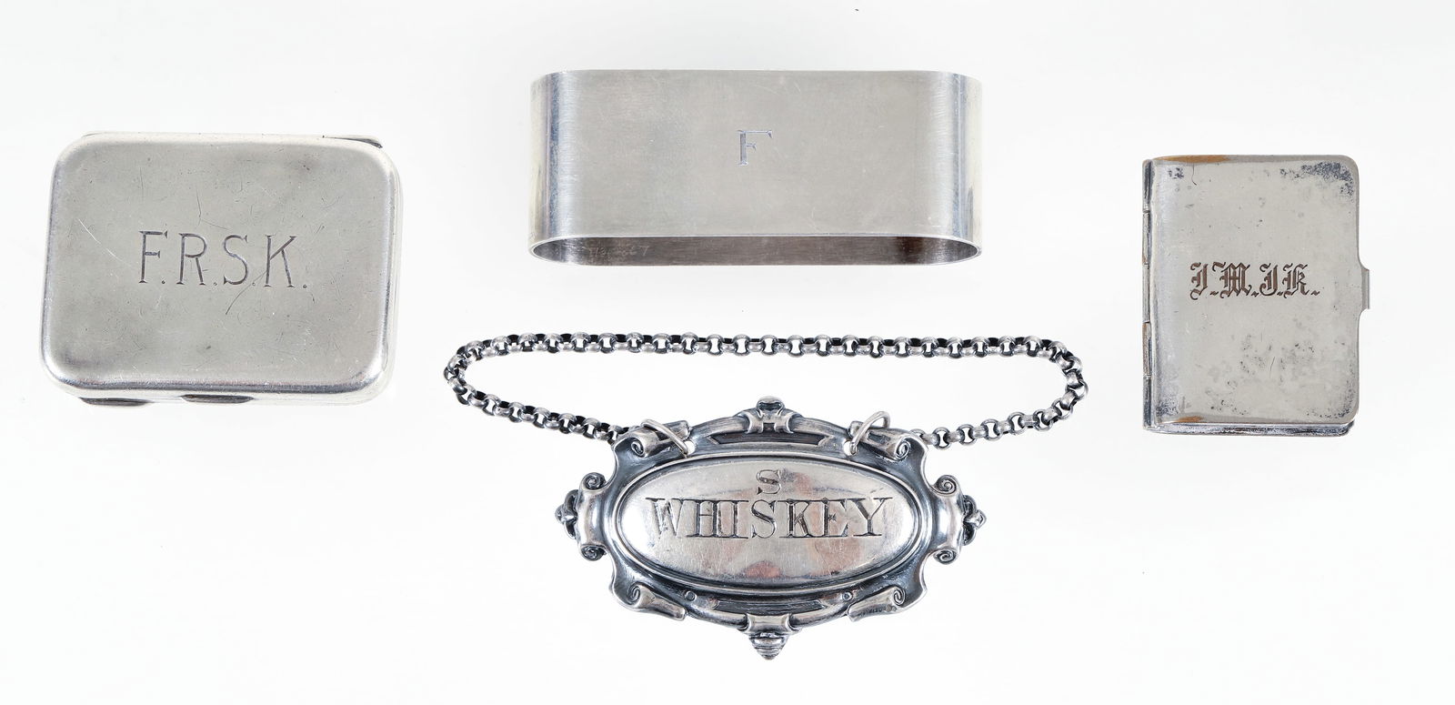 Assorted Silver Pieces: Assorted silver pieces, includes several vintage pill boxes, napkin ring and a whiskey bottle tag. One of the sterling boxes is engraved "F.R.S.K."Measures 2" in length, 1 1/16" wide, 7/16" deep. Made