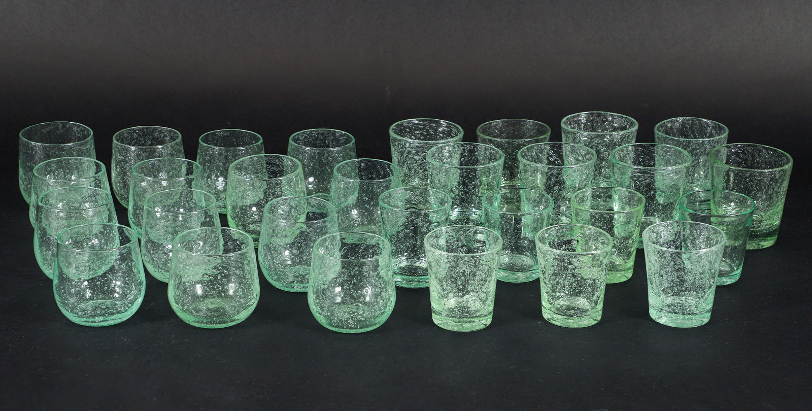 Group of 29 assorted Verrerie de Biot Green Bubble Glassware: Verrerie de Biot Green Bubble Glassware, Includes 7 Juice Glasses 3.5 inches tall, 14 water glasses 3.5 inches tall, 8 Cocktail (Rocks) Glasses 4.25 inches tall, marked with Biot on undersides.