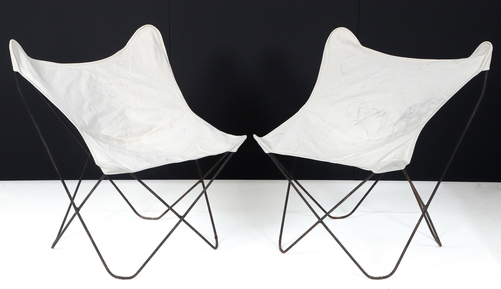 2 Butterfly Chairs w/ White Slings: 2 Butterfly chairs with white canvas slings. 32-35 inches in height, 30-35 inches in width, and 26-30 inches in depth.