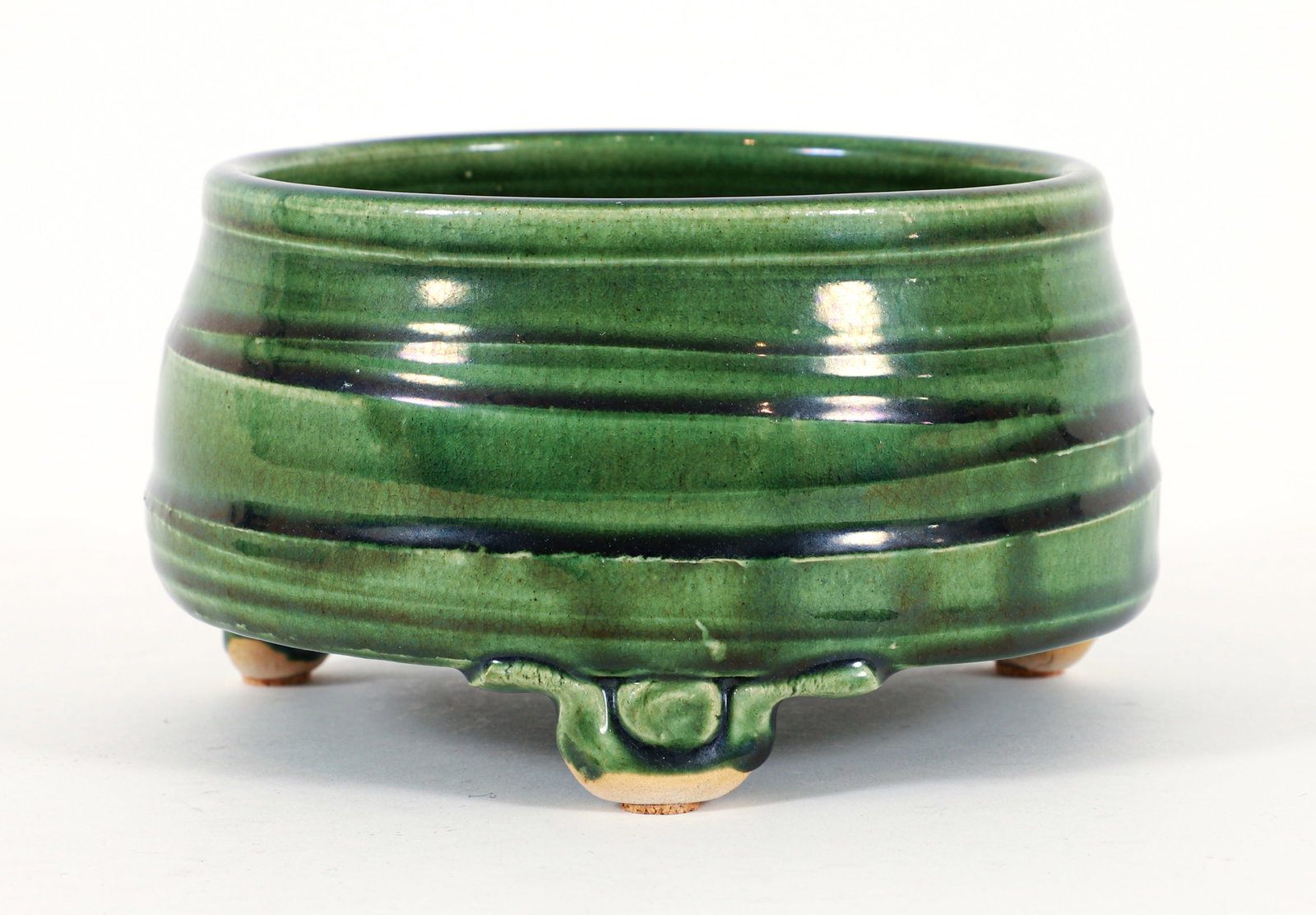 Warren MacKenzie Shallow Circular Earthenware Bowl: Warren MacKenzie Earthenware. Shallow circular form on tripod feet with pronounced throwing lines surrounding the form. Covered in a glassy green 'American Oribe' glaze. Impressed 'WM' seal.