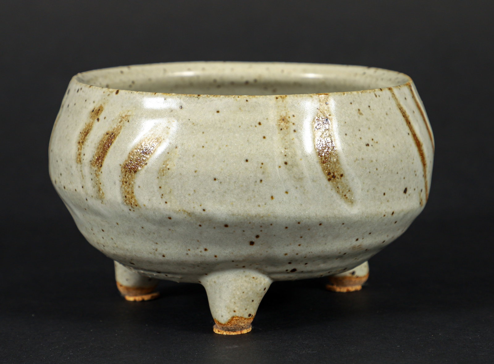 Warren MacKenzie Shallow Circular Earthenware Bowl: Warren MacKenzie Stoneware. Cylindrical form on 3 pedestal feet. Covered in a waxy white glaze with finger wipe decorations repeating around the midsection. Impressed WM seal.