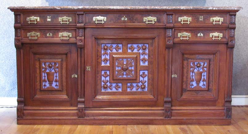 American Aesthetic Movement Walnut Sideboard: Title: American Aesthetic Movement Walnut Sideboard with carved door panels with stylized flowers and leaves. With interesting brass pulls decorated to match carved door panels and marble top Date: ci