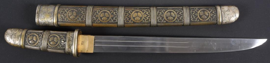 JAPANESE TANTO: JAPANESE TANTO Ken horimono (religious engraving) on front of blade. Gomabashi (twin chopstick) horimono on reverse. High relief metal shirasaya with a three leaf in a circle pattern. Hamon: Suguba (s