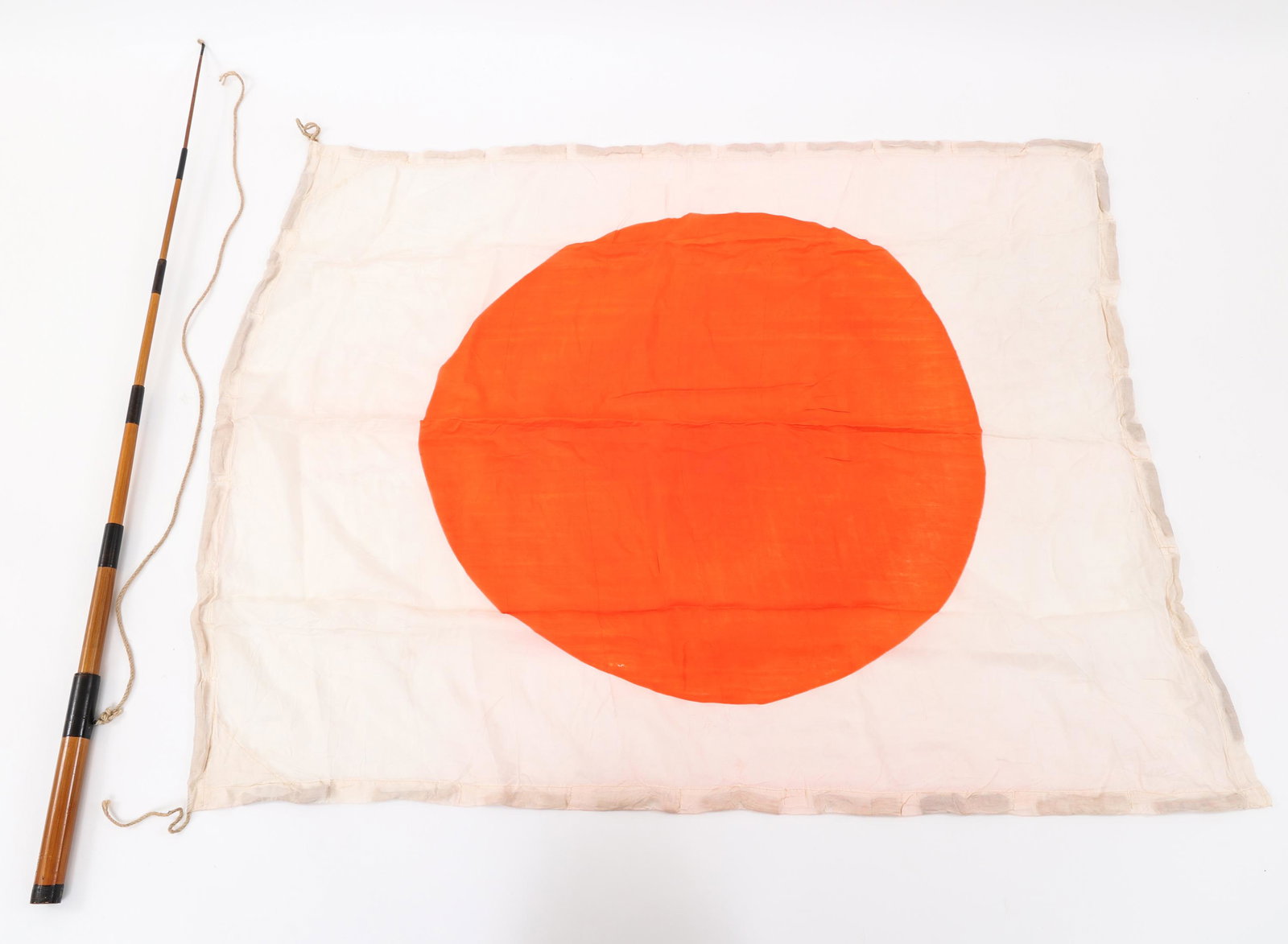 WWII JAPANESE PILOT BAIL OUT FLOAT FLAG & STAFF: WWII JAPANESE PILOT BAIL OUT FLOAT FLAG & STAFF World War II Japanese pilot’s bail-out survival meatball float flag. The flag is constructed of silk with a stitched and stuffed buoyant border to ass