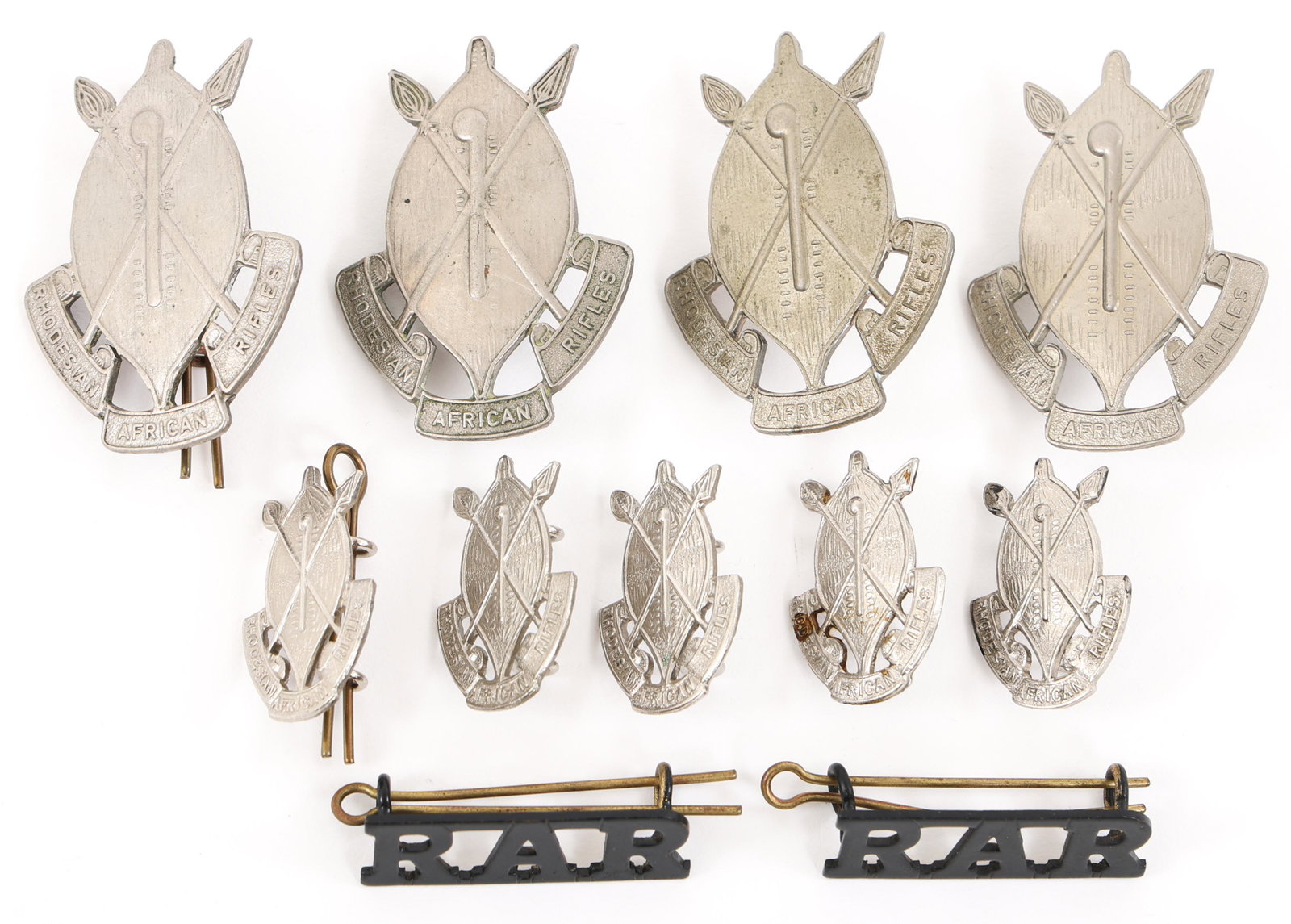 RHODESIAN AFRICAN RIFLES CAP BADGE & COLLAR LOT: RHODESIAN AFRICAN RIFLES CAP BADGE & COLLAR LOT Lot of 11 Rhodesian African rifles R.A.R insignia. (4) R.A.R. Cap Badges. (5) R.A.R Collar Insignia. (2) R.A.R. Blackened Brass Shoulder Title. Provenan