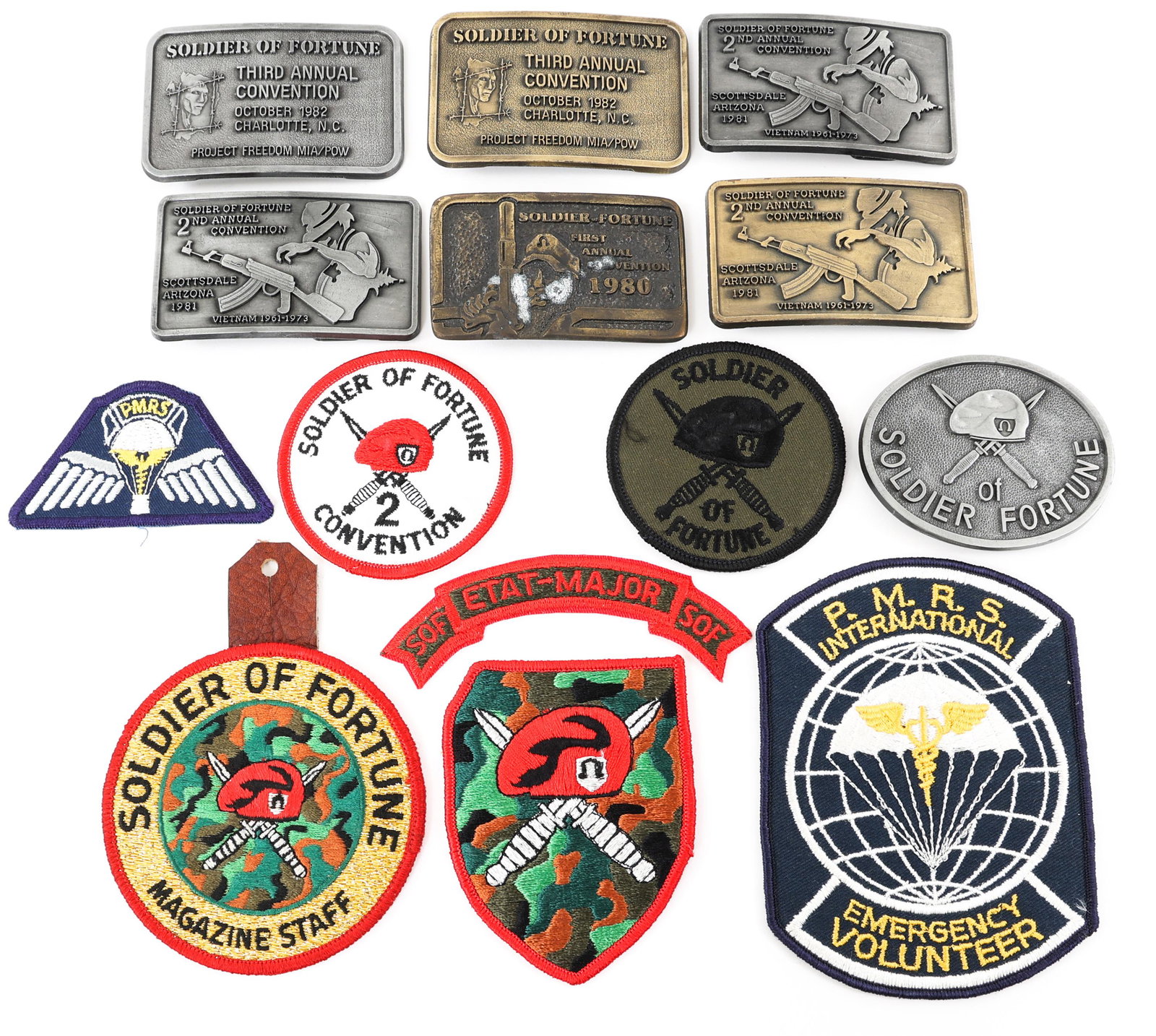 SOLDIER OF FORTUNE CONVENTION PATCHES & BUCKLES: SOLDIER OF FORTUNE CONVENTION PATCHES & BUCKLES Soldier of Fortune Convention Patches & Belt Buckles lot. Provenance | The Dublin Trust Collection: Personal effects of a U.S. Citizen, who arrived in t