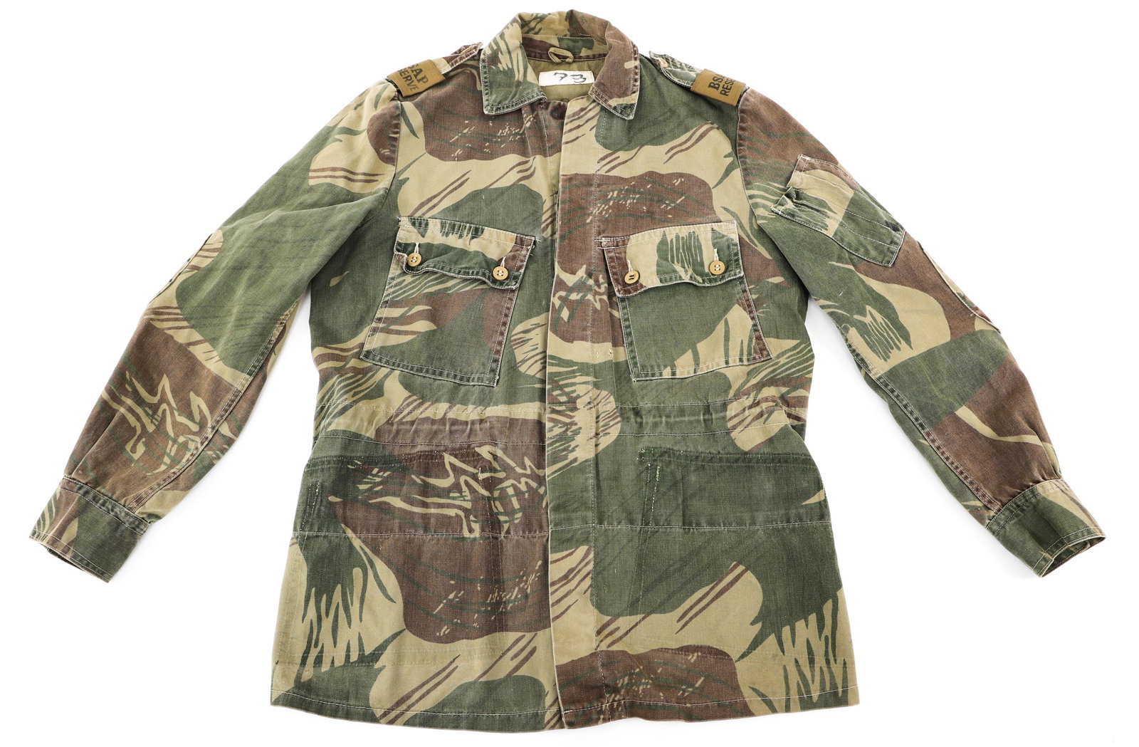 RHODESIAN BUSH WAR BRUSHSTROKE CAMO FIELD JACKET: RHODESIAN BUSH WAR BRUSHSTROKE CAMO FIELD JACKET Rhodesian Bush War "Brushstroke" Camo Field Jacket with Hand Written name inside. Lower pockets removed. BSAP reserve shoulder boards. Light khaki butt