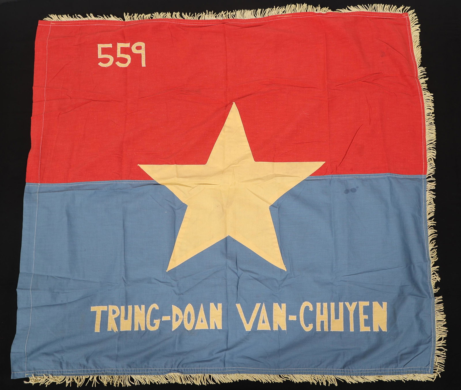 VIETNAM WAR VIET CONG 559th TRANPORT GROUP FLAG: VIETNAM WAR VIET CONG 559th TRANPORT GROUP FLAG Viet Cong 559th Transport Group Flag. Blue and red multi-piece cloth construction. Gold fringe border, Yellow 5 point star center, and "Trung-Doan Van-C
