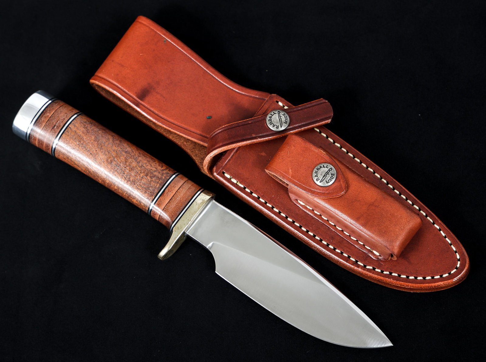 RANDALL MODEL 25 TRAPPER KNIFE & LEATHER SHEATH: RANDALL MODEL 25 TRAPPER KNIFE & LEATHER SHEATH Randall Model 25 Trapper Knife and Leather sheath. Drop point, bright, slightly curved blade. Maker mark / logo "Randall Made Orlando, FLA". Brass half 