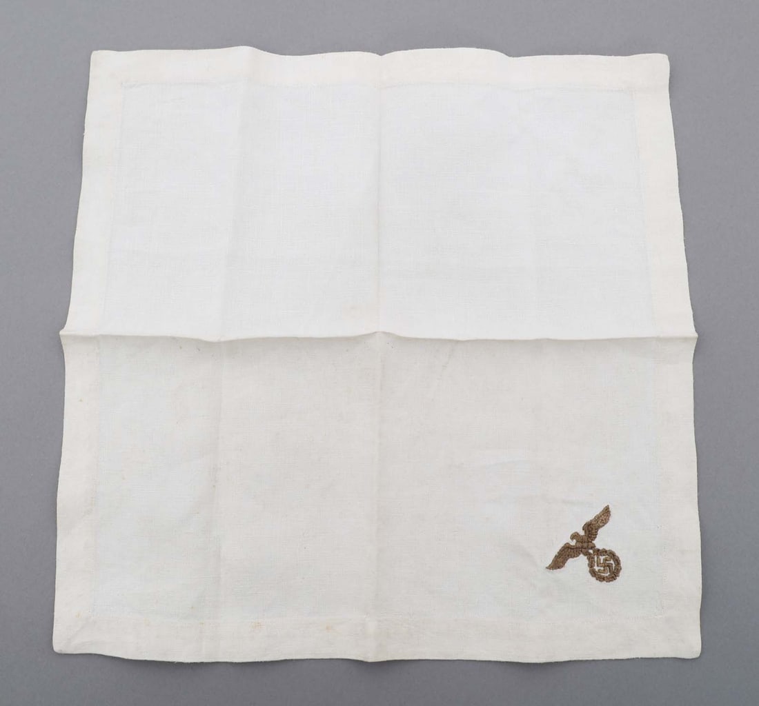 WWII GERMAN NSDAP POLITICAL DINNER NAPKIN: WWII GERMAN NSDAP POLITICAL DINNER NAPKIN WWII German NSDAP Political Dinner Napkin. White, linen construction with embroidered NSDAP Eagle on the corner. No visible maker mark. Size: 13" x 13 1/2"