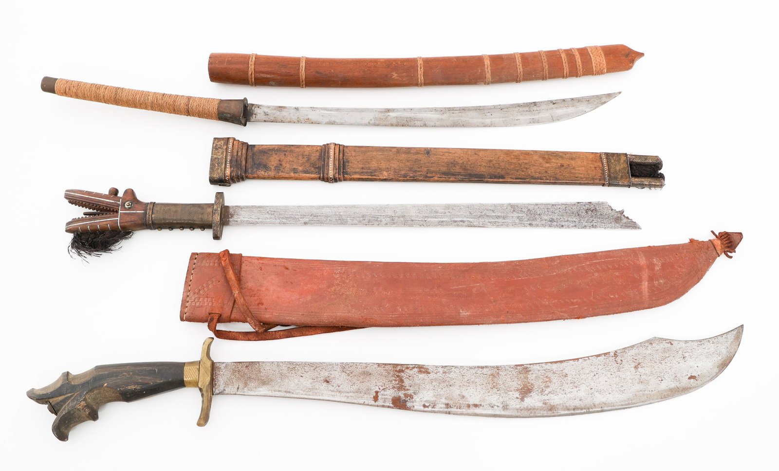 SOUTHEAST ASIAN KAMPILAN, PIRA & DHA SWORDS: SOUTHEAST ASIAN KAMPILAN, PIRA & DHA SWORDS Southeast Asian Kampilan, Pira and Dha Swords. (1) Kampilan. Wooden scabbard with brass fittings. (1) Pira. Leather scabbard. (1) Dha. Single edged blade. W