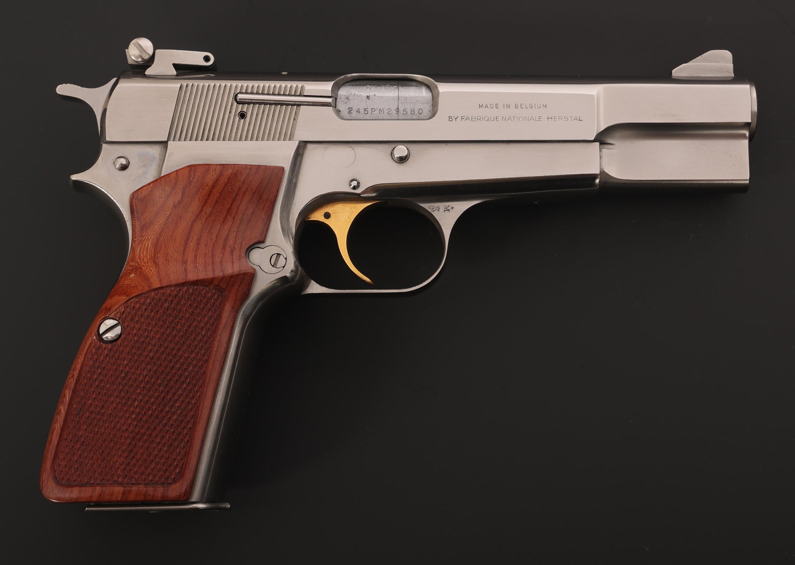 BROWNING MODEL HI-POWER 9x19mm CALIBER PISTOL: BROWNING MODEL HI-POWER 9x19mm CALIBER PISTOL Browning Model Hi-Power 9x19mm caliber semi-automatic pistol. Checkered wood grips. Gold accented trigger. Blade front sight. Adjustable rear sight. Two m