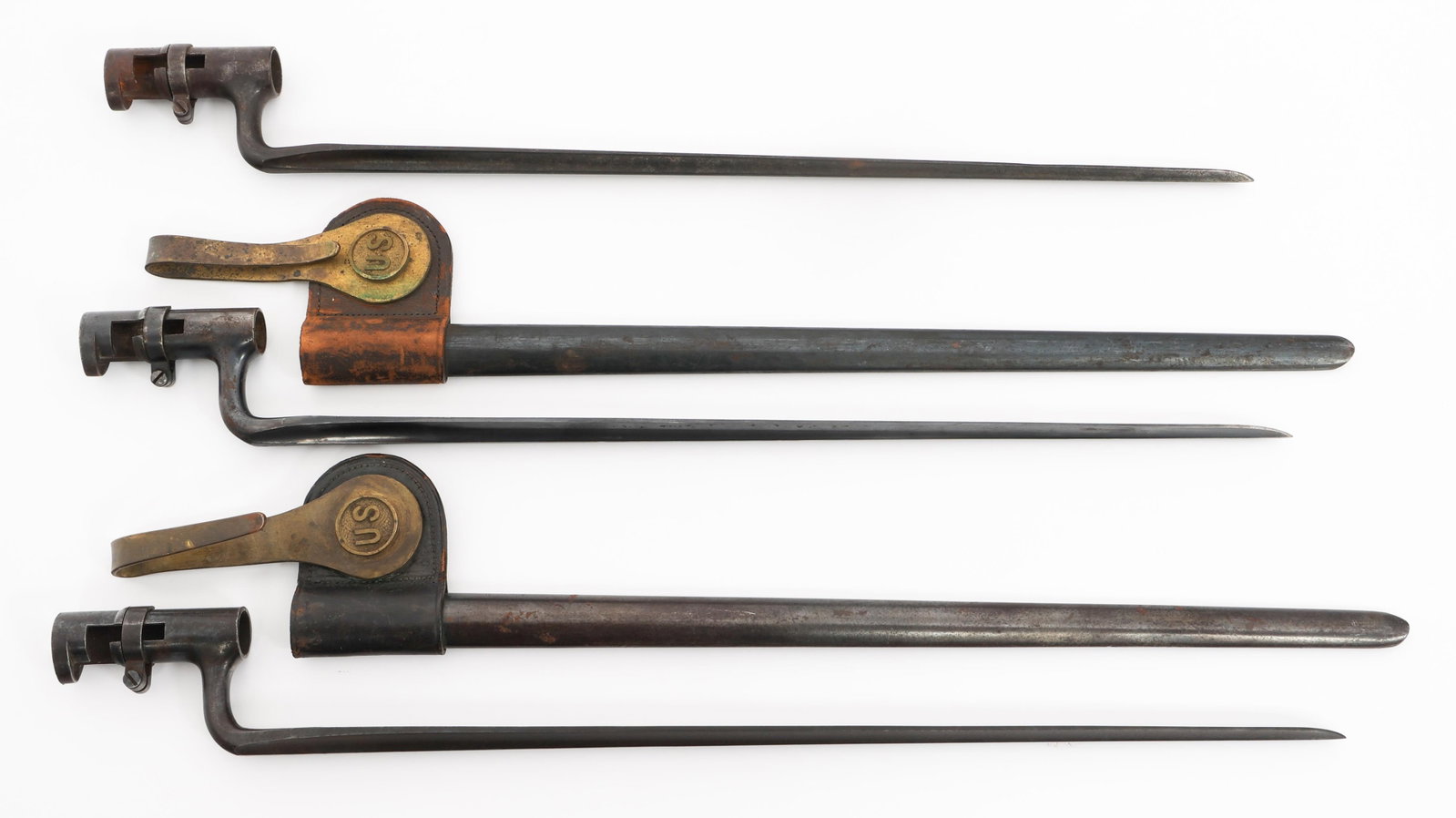 US ARMY MODEL 1873 SOCKET BAYONETS: US ARMY MODEL 1873 SOCKET BAYONETS Three US Army Model 1873 Socket Bayonets. Blued triangular blades with fullers. "US" stamped on the ricassos. Two have blued steel scabbards with leather and brass f