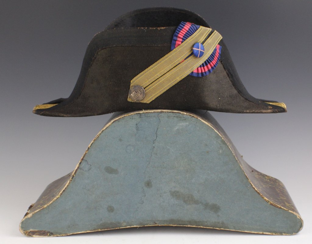 CIVILIAN OFFICIAL CHAPEAU DE BRAS: A civilian official's Chapeau de Bras, composed of beaver pelt in bicorn form. 1" black ribbon follows top rim on both sides. A grosgrain cockade blue and red in color is mounted to the top of one fol