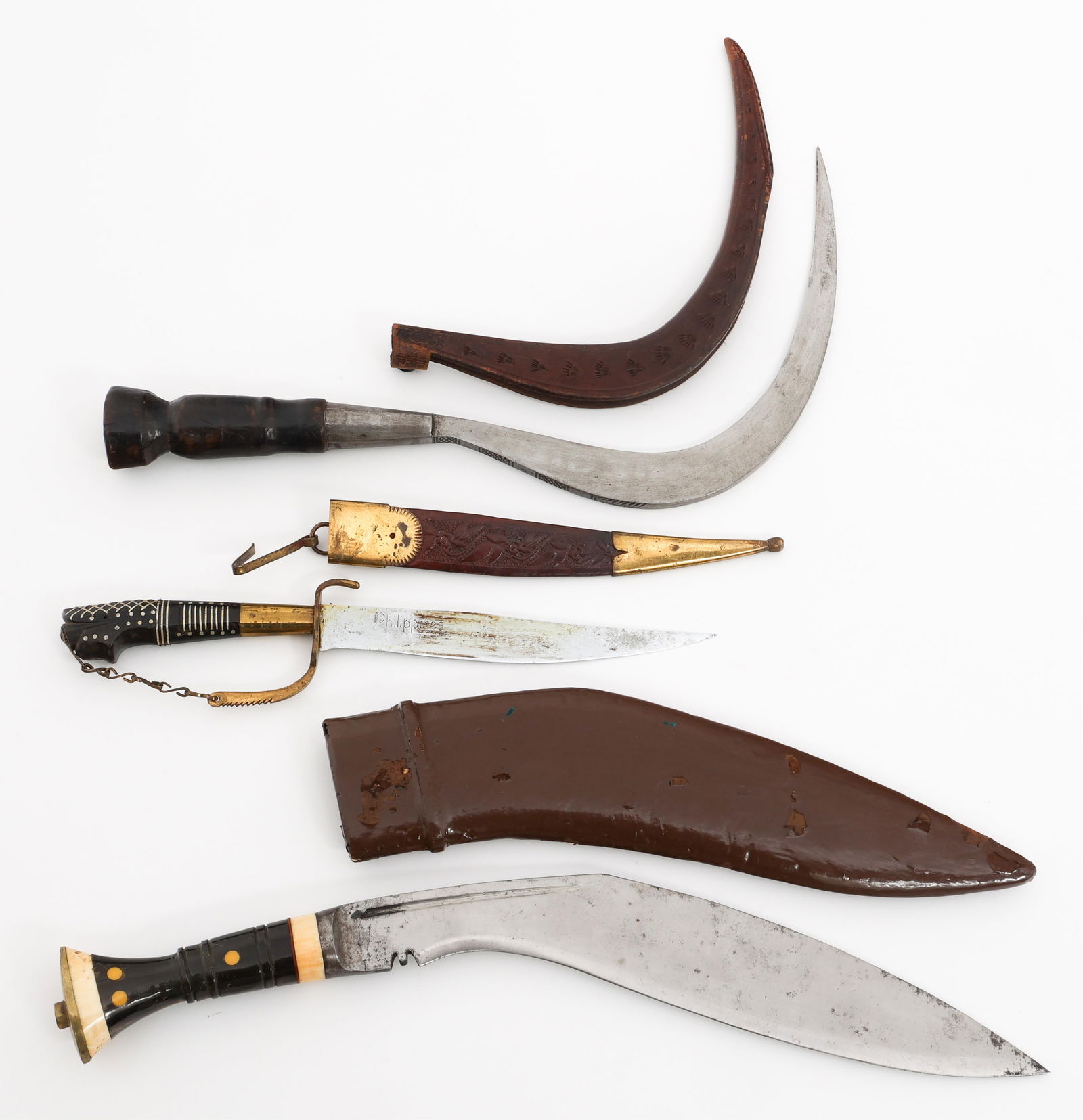 SOUTHEAST ASIAN TOURIST KUKRI, DAGGER & CELURIT: SOUTHEAST ASIAN TOURIST KUKRI, DAGGER & CELURIT Southeast Asian Tourist Kukri, Dagger and Celurit. (1) Kukri. Brown painted wooden scabbard. (1) Dagger. Philippines etched onto the blade. Wooden and l