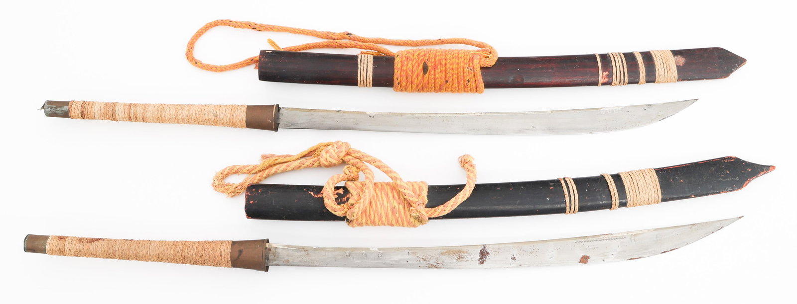 THAI DHA SWORDS: THAI DHA SWORDS Two Thai Dha Swords. Single edged blades with no visible marks or stamps. Brass hilts with rattan wrapped grips. Wood scabbards. Blade Length: 20" Total Length: 31"