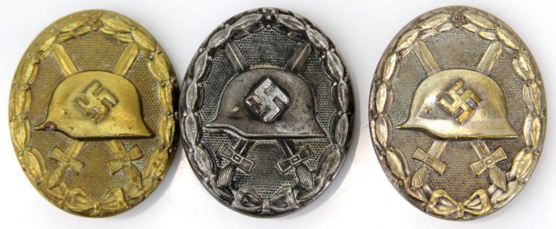 THREE WWII GERMAN WOUND BADGES: THREE WWII GERMAN WOUND BADGES Three WWII German wound badges. Silver and gold toned badges marked "L14" on back, with coke bottle pins. Black wound badge is stamped construction, with wire pin on bac
