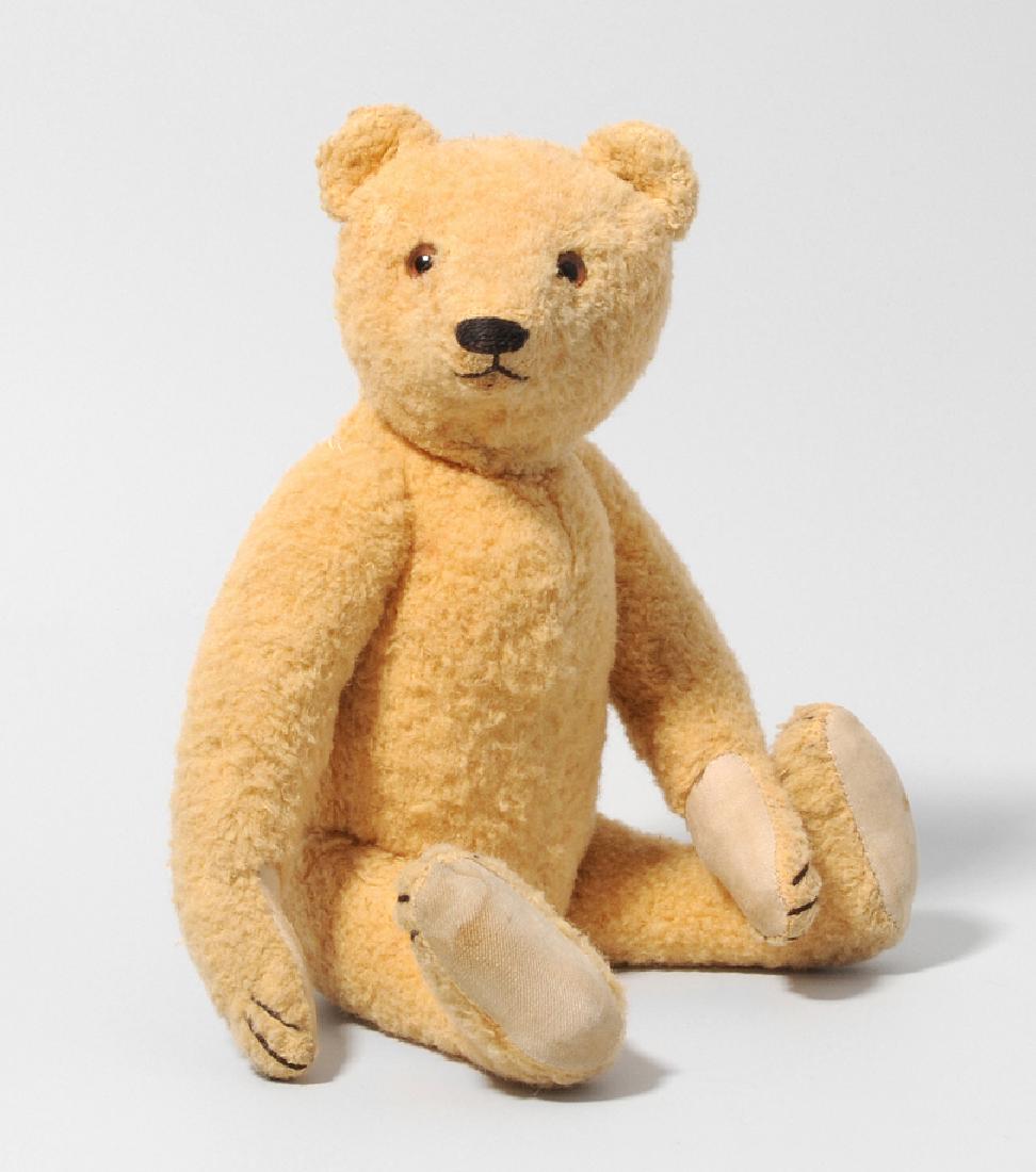 (Steiff-)Teddybär Deutschland, um 1920. Gegliederter: (Steiff-)Teddybär Deutschland, um 1920. Gegliederter Körper aus blondem Seidenplüsch. Braune Glasaugen. Mund, Nase und Krallen (neu) gestickt. Sohlen aus Stoff. Ohne Marke. H 29 cm. - Leicht abgeli