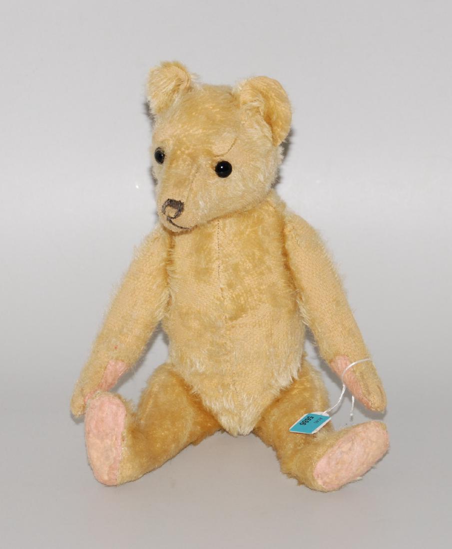 Teddybär Um 1920/30. Aus beigem Plüsch mit schwarzen: Teddybär Um 1920/30. Aus beigem Plüsch mit schwarzen Glasaugen (wohl ersetzt). H 32 cm. - Stark abgeliebt.