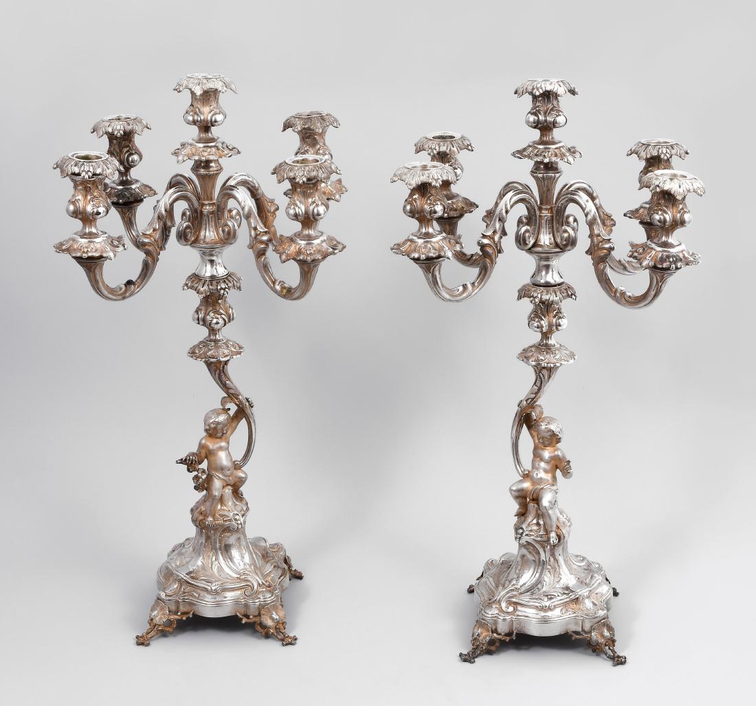 1 Paar Girandolen Paris, 1911–16. Silber. Meistermarke: 1 Paar Girandolen Paris, 1911–16. Silber. Meistermarke Alphonse Debain. Fassonierter Sockel auf Astbeinen, darüber Putto mit 5-flammigem Leuchter. Reliefierter Blattdekor begleitet von Kartuschen u