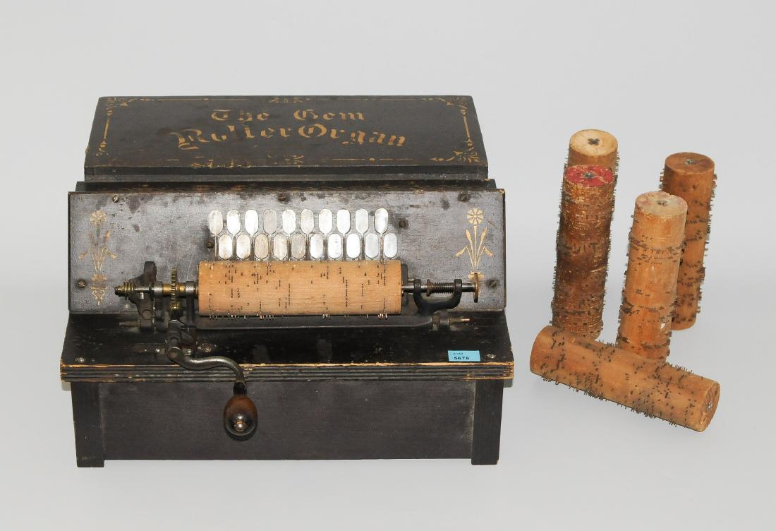 Walzenorgel USA, um 1897. Bezeichnet: "The Gem Roller: Walzenorgel USA, um 1897. Bezeichnet: "The Gem Roller Organ". Hersteller:" C. Borden & Co". Schwarz bemaltes Holzgehäuse mit goldfarbenem Floral- bzw. Ornamentaldekor. Drehmechanik und Verschlussklap