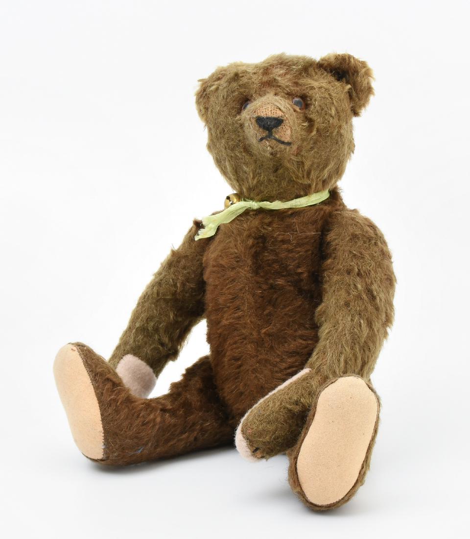 Steiff-Teddybär Deutschland, um 1940/50. Gegliederter: Steiff-Teddybär Deutschland, um 1940/50. Gegliederter Körper aus dunkelbraunem Mohairplüsch. Braune Glasaugen. Nase, Mund und Krallen gestickt. Fussohlen aus Filz ersetzt. Mit Knopf. H 30 cm. - Abg