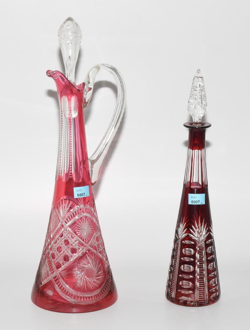 2 Karaffen Um 1900. Wohl Val St. Lambert. Verschieden: 2 Karaffen Um 1900. Wohl Val St. Lambert. Verschieden in Form, Grösse und Dekor. Farbloses Kristallglas, rot bzw. purpurfarben überfangen, Schliffdekor. H 42 bzw. 34 cm.