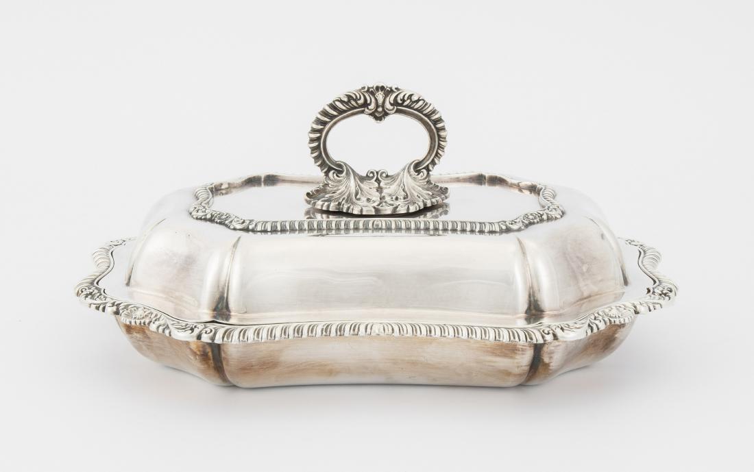 Deckelterrine: England, um 1900. Versilbert. Fassonierte Form mit Godronen- und Blattbordüren, gewölbter Deckel mit abnehmbarem Ringhenkel. 30x22 cm.