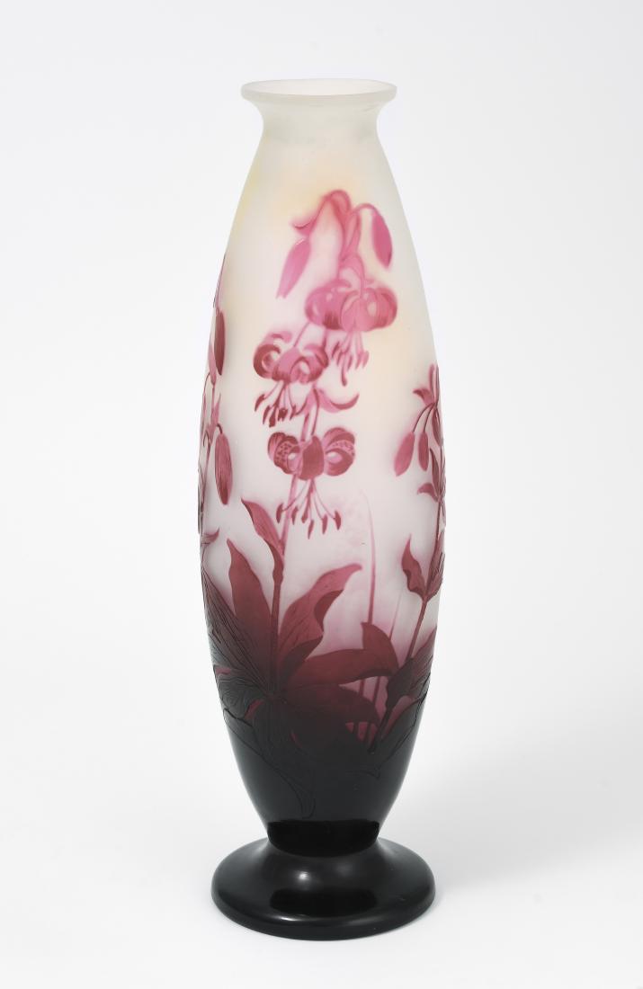 Emile Gallé: Nancy. Vase. Farbloses opakes Glas, purpurfarben überfangen, umlaufend reliefiert geätzter Dekor mit Türkenbund. Bezeichnet: Gallé (hochgeätzt). H 38 cm. - Mündung nachgeschliffen.