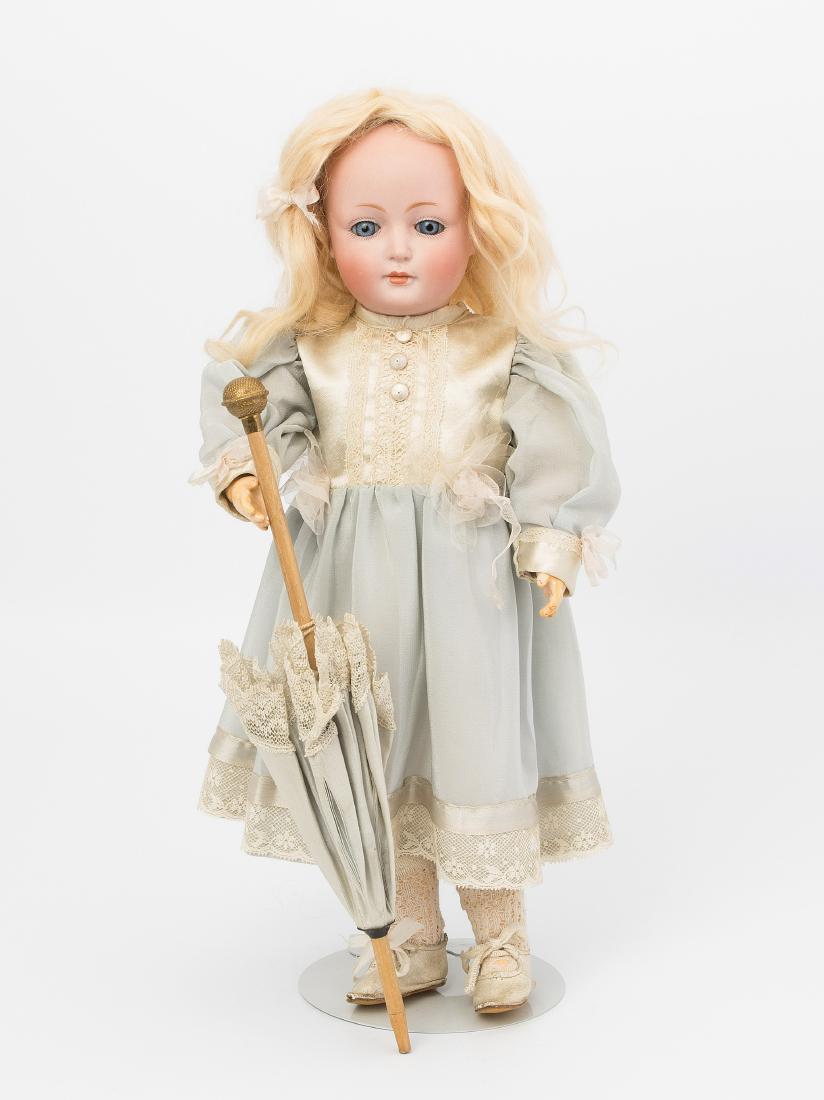 J.D. Kestner jr.-Charakterpuppe "182": Deutschland, um 1910. Kurbelkopf mit Schlafaugen und geschlossenem Mund aus Biscuit-Porzellan. Halsmarke: "182.". Gelenkkörper aus Masse. Blonde Mohairperücke. Bekleidung im alten Stil. H 38 cm. - L