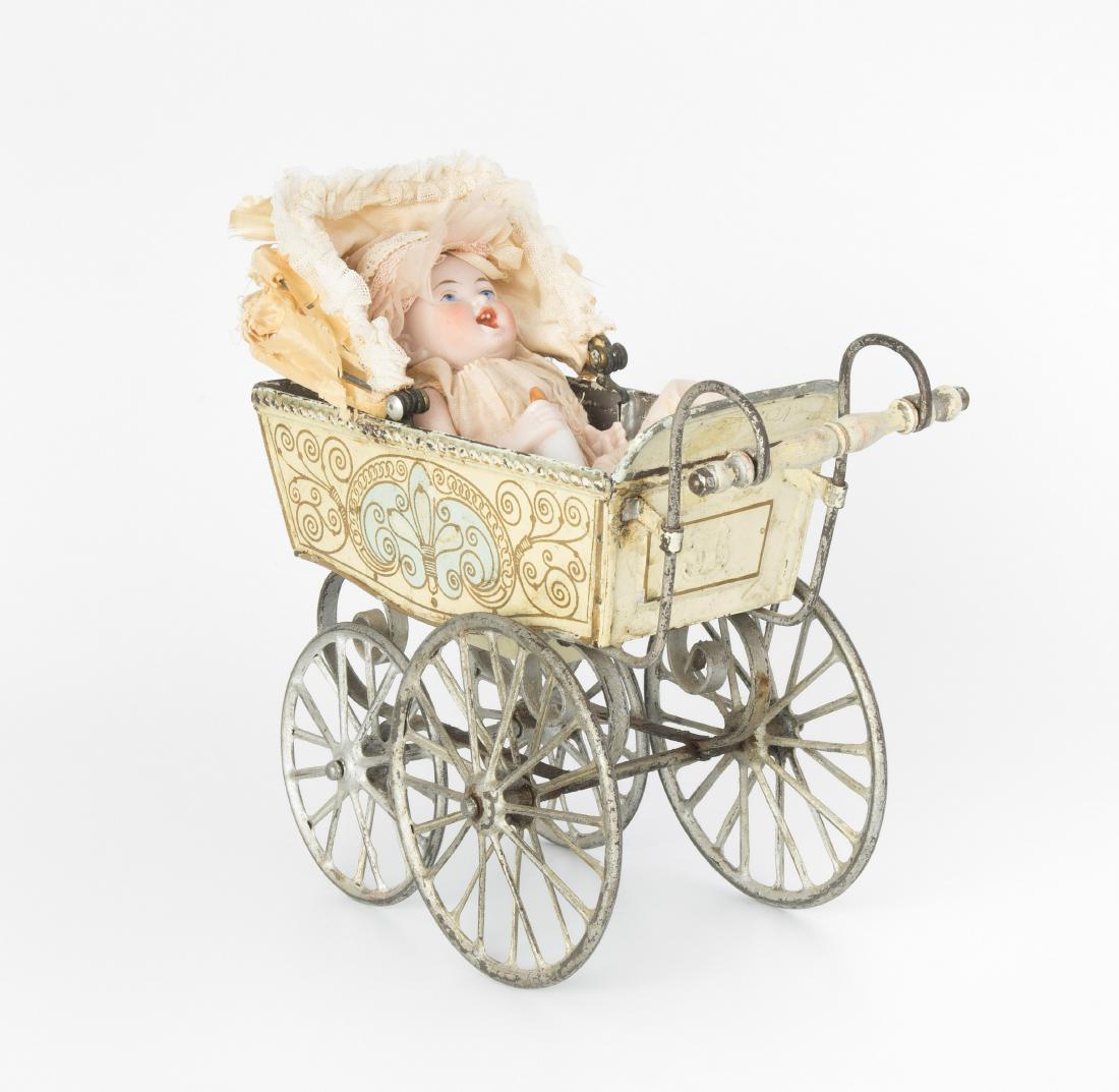Märklin-Puppenwagen mit Babypuppe: Deutschland, um 1910/20. (1) Puppenwagen aus farbig lackiertem Metallblech. Goldener Ornamentaldekor auf beigem Grund. Verdeck aus Seide (stark brüchig). L 20 cm. (2) Babypuppe mit Fläschchen ganz a