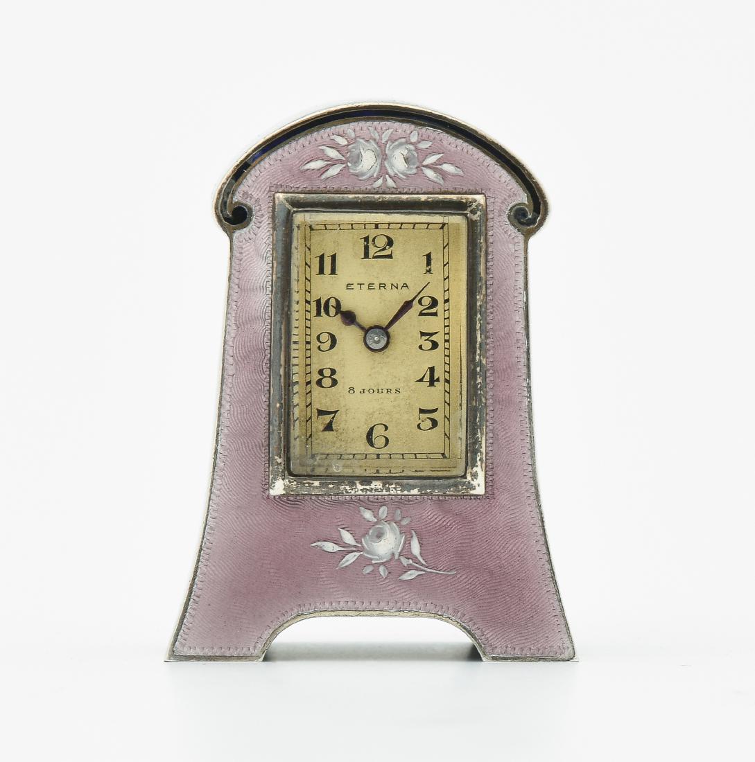 Kleine Tischuhr Eterna: Schweiz, 20.Jh. Vergoldetes, mit verziertem Email überzogenes Gehäuse. Beiges, rechteckiges Zifferblatt mit arabischen Zahlen und Signatur "Eterna". Unruhewerk zu revidieren. 5x4 cm.
