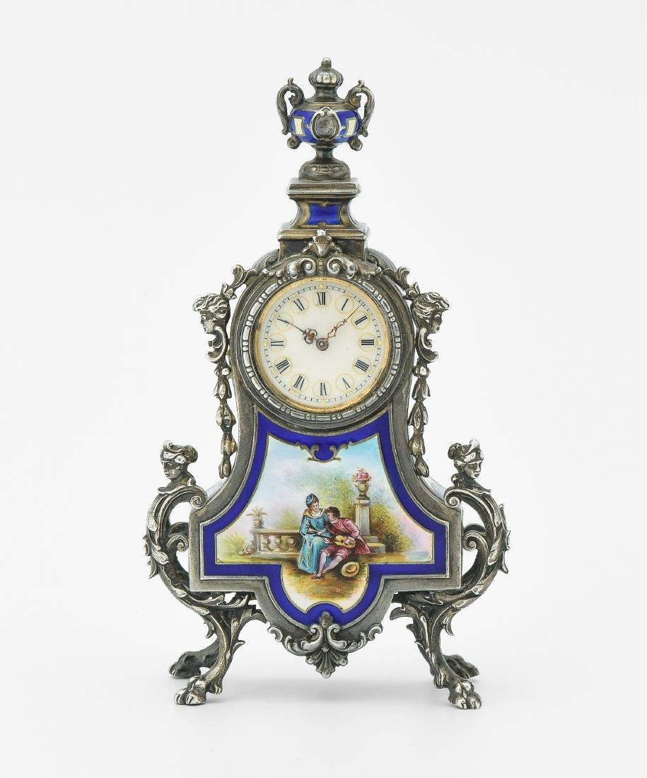 Kleine Tischuhr Eterna: Schweiz, 20.Jh. Verziertes Metallgehäuse, allseitig mit Emailmalereien versehen und Vasenkrönung. Weisses Emailzifferblatt mit römischen Zahlen. Unruhewerk, gehfähig. 13x7 cm.