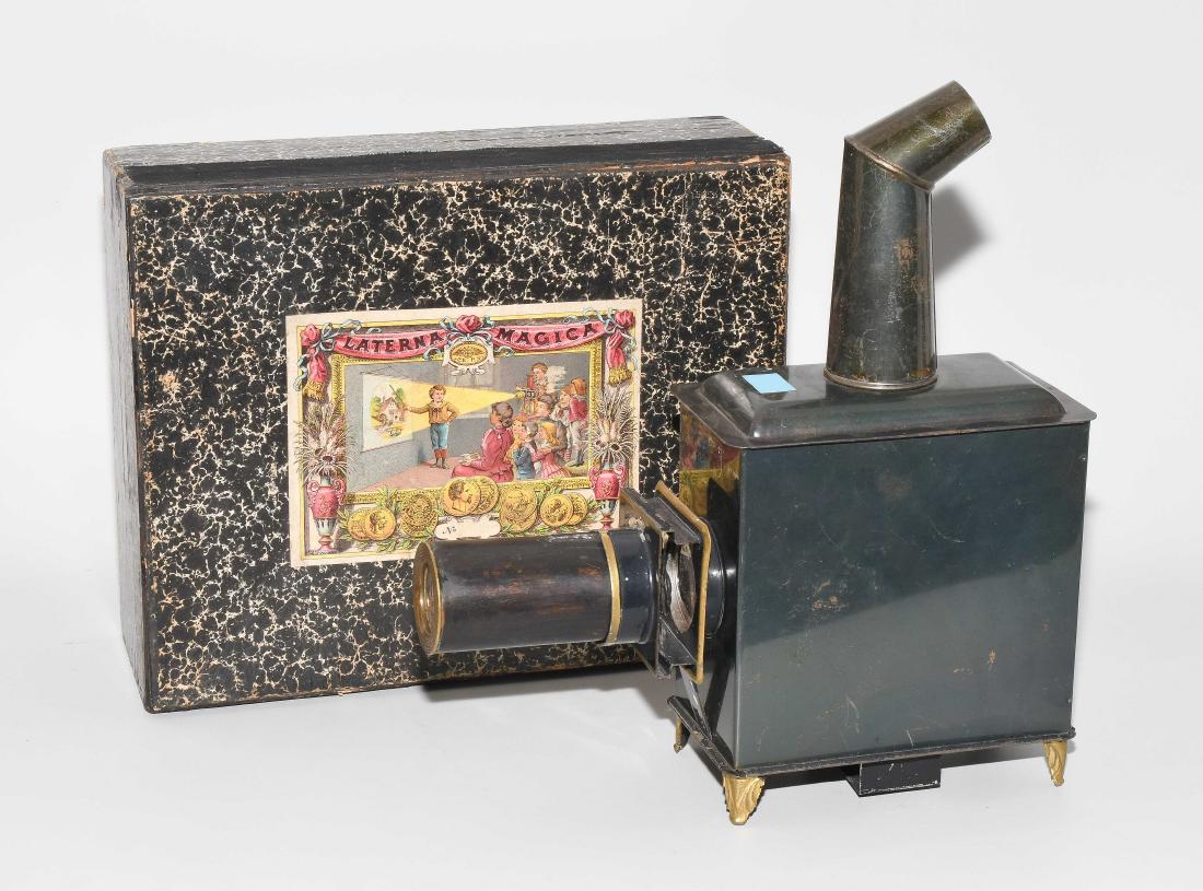 Kleine Laterna Magica: Deutschland, um 1900. Hersteller: "Ernst Plank, Nürnberg". Blechgehäuse mit Objektiv und Kamin. Für Glasbilder mit einer Höhe von 6 cm. In Originalkarton. Dazu Sammlung Durchziehbildchen mit Kinde