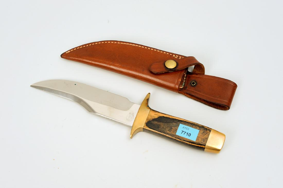 Waidmesser: Smith & Wesson, USA, um 1980. Stahlklinge, in der Angel Firmenmarke und Jahreszahl 1979, Nr. 20731. Hartholzgriff mit Messingbeschlägen. Original-Lederscheide. L ca. 26 cm.