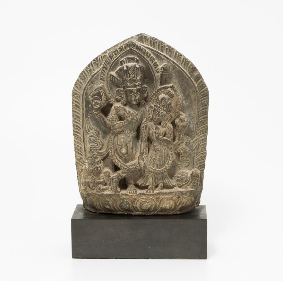 Kleine Stele: Nepal, 16./17.Jh. Harter, grauer Stein, vermutlich Schiefer. Darstellung des stehenden Götterpaares Vishnu und Parvati. H 24. Montiert auf schwarzem Sockel, H 28 cm.
