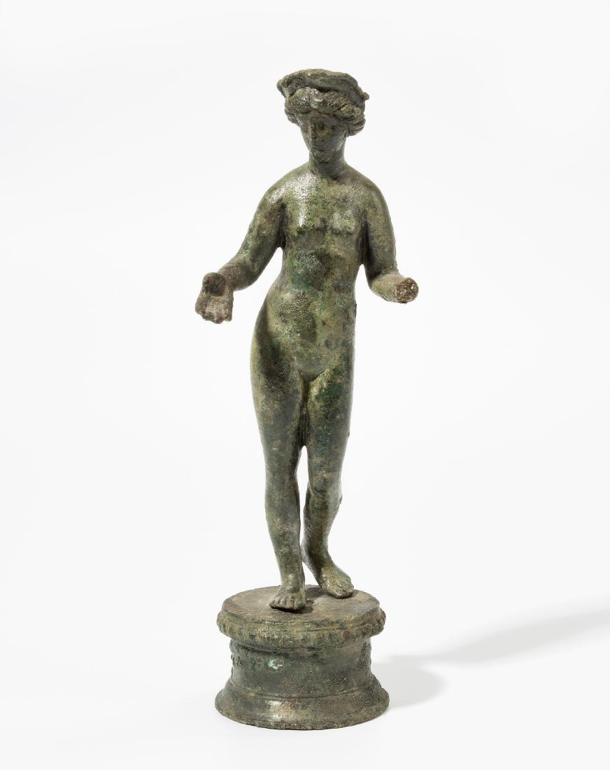 Statuette der Venus: Römisch, 1.–2.Jh. n.C. Bronzevollguss. In leichtem Kontrapost stehende Venus mit Diadem, beide Arme angewinkelt, die Handfläche nach oben. H 15,9, H mit Sockel 19 cm. - Linke Hand fehlt, rechte Ha