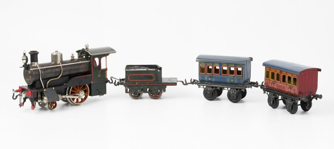Bing-Modelleisenbahn: Deutschland, um 1910. Blech, farbig lackiert. Spur I, 2-achsig. Bestand: (1) Dampfbetriebene "Storchenbein"-Lokomotive "I 48" mit Tender und Original-Brenner. L 23/14 cm. (2) Abteilwagen, "I" und "II"