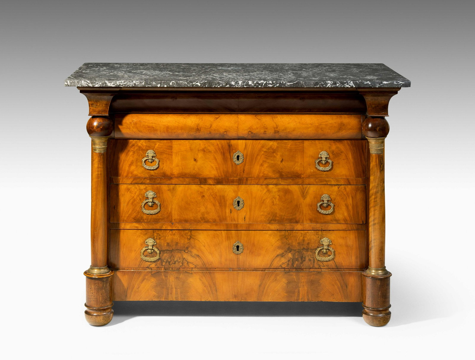 Kommode: Biedermeier ca. 1820, Nussbaum, Marmor. Vierschübiger Korpus, mit seitlichen Vollsäulen gearbeitet. Front mit durchgehendem Furnierbild versehen. Marmor: Grau - Beige gemustert. Guter Zustand. 133x6