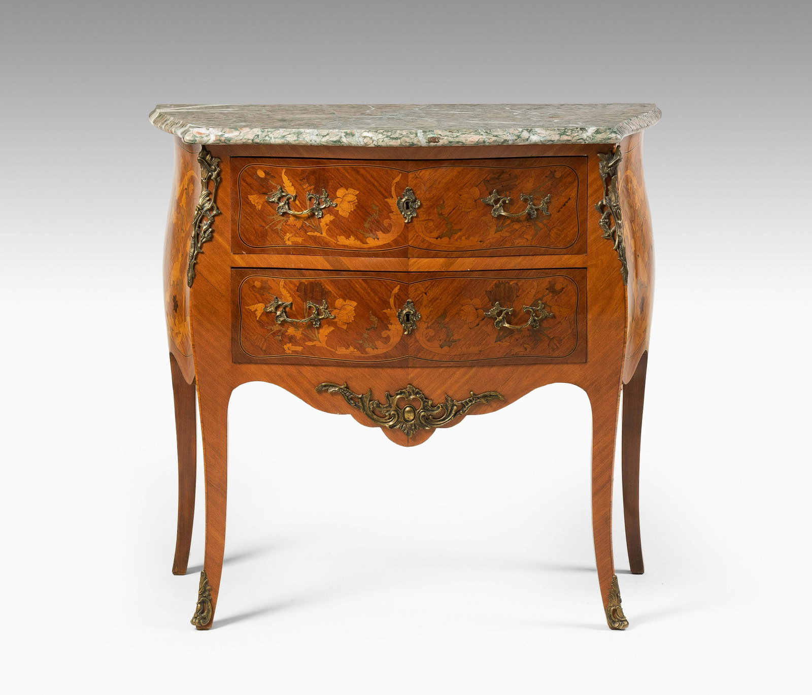 Kommode: Louis XV- Stil, 20. Jh. Rosenholz und Ahorn, Marmor. Zweischübiger, bombierter Korpus, auf hohen schlanken Beinen. Dreiseitig gefeldert furniert, mit floralem Dekor intarsiert. Marmor: Grün - Grau g
