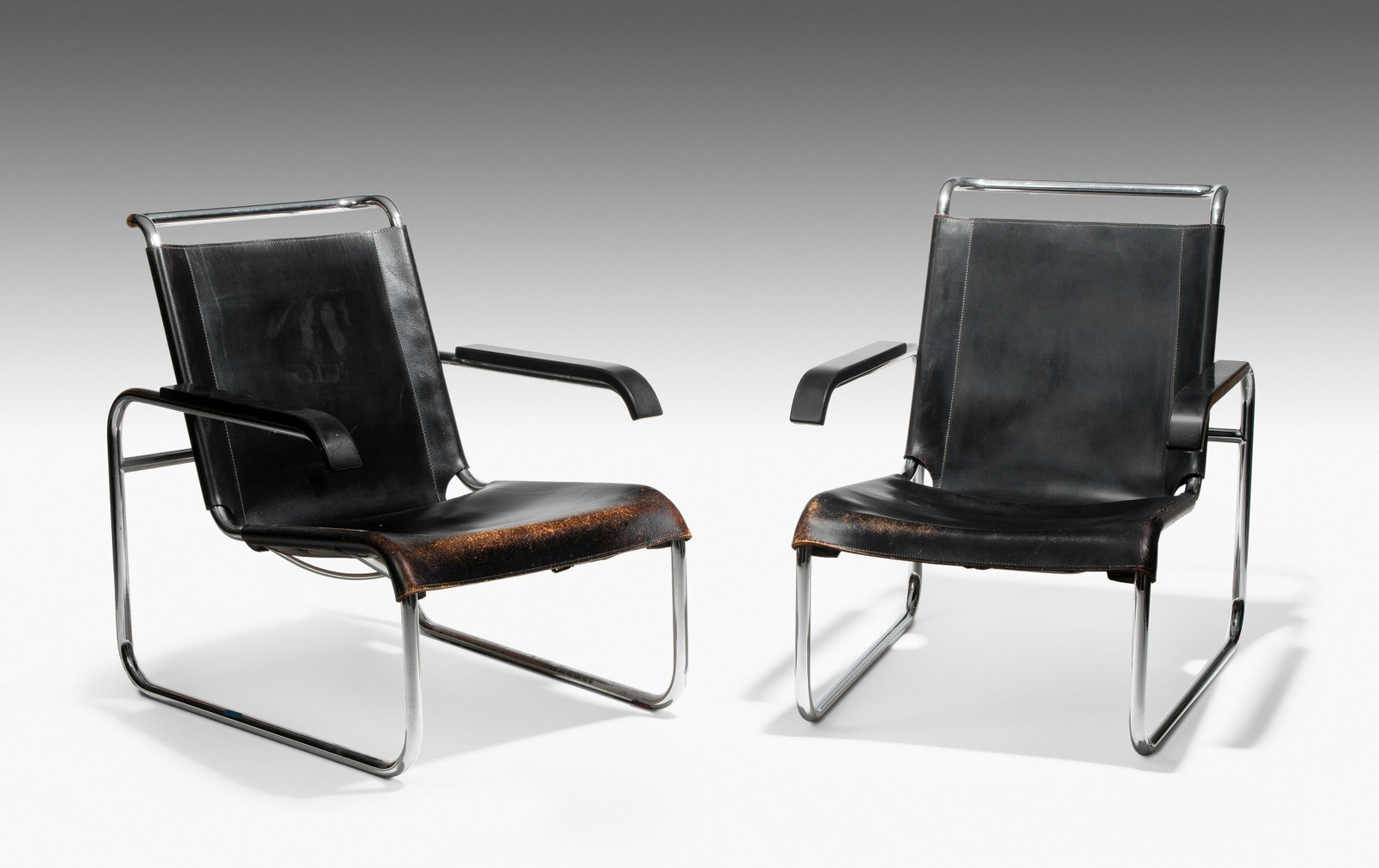 Marcel Breuer für Thonet: 2 Armlehnsessel "S 35". Entwurf:1928/1929. Ausführung seit 1930. Stahlrohr, schwarzes Leder, Armlehnen aus schwarz gebeiztem Holz. Beide Stühle mit originalem Papieretikett "THONET". 65x83x79 cm. - 