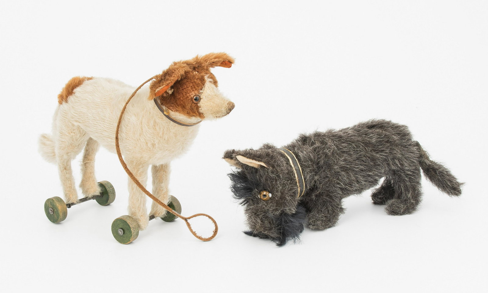 Lot: 2 Steiff-Hunde: Deutschland, um 1930. (1) "Scotty". Mohairplüsch, grauschwarz. Glasaugen. Stehender Scottish Terrier mit Halsmechanik. Mit Knopf. H 11 cm. (2) Kleines Ziehtier, St. Bernhard. Mohairplüsch weiss, bra