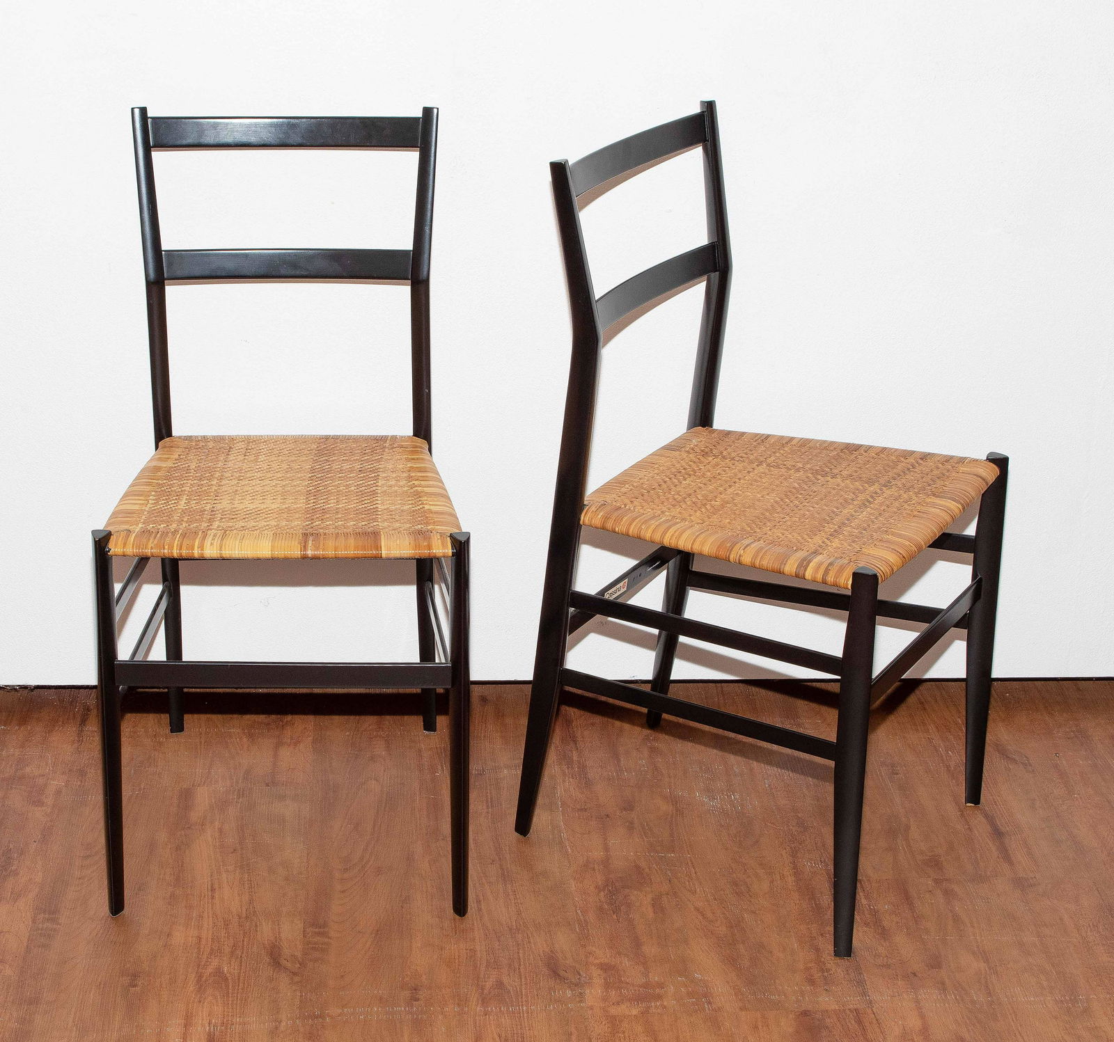 Gio Ponti: 4 Stühle "699 Superleggera". Entwurfsjahr: 1957; Ausführung: Cassina. Vertrieb: Wohnbedarf AG Schweiz. Esche, schwarz lackiert, Sitzfläche aus Spanischem Rohr. Bezeichnet: Cassina (Papieretikett),