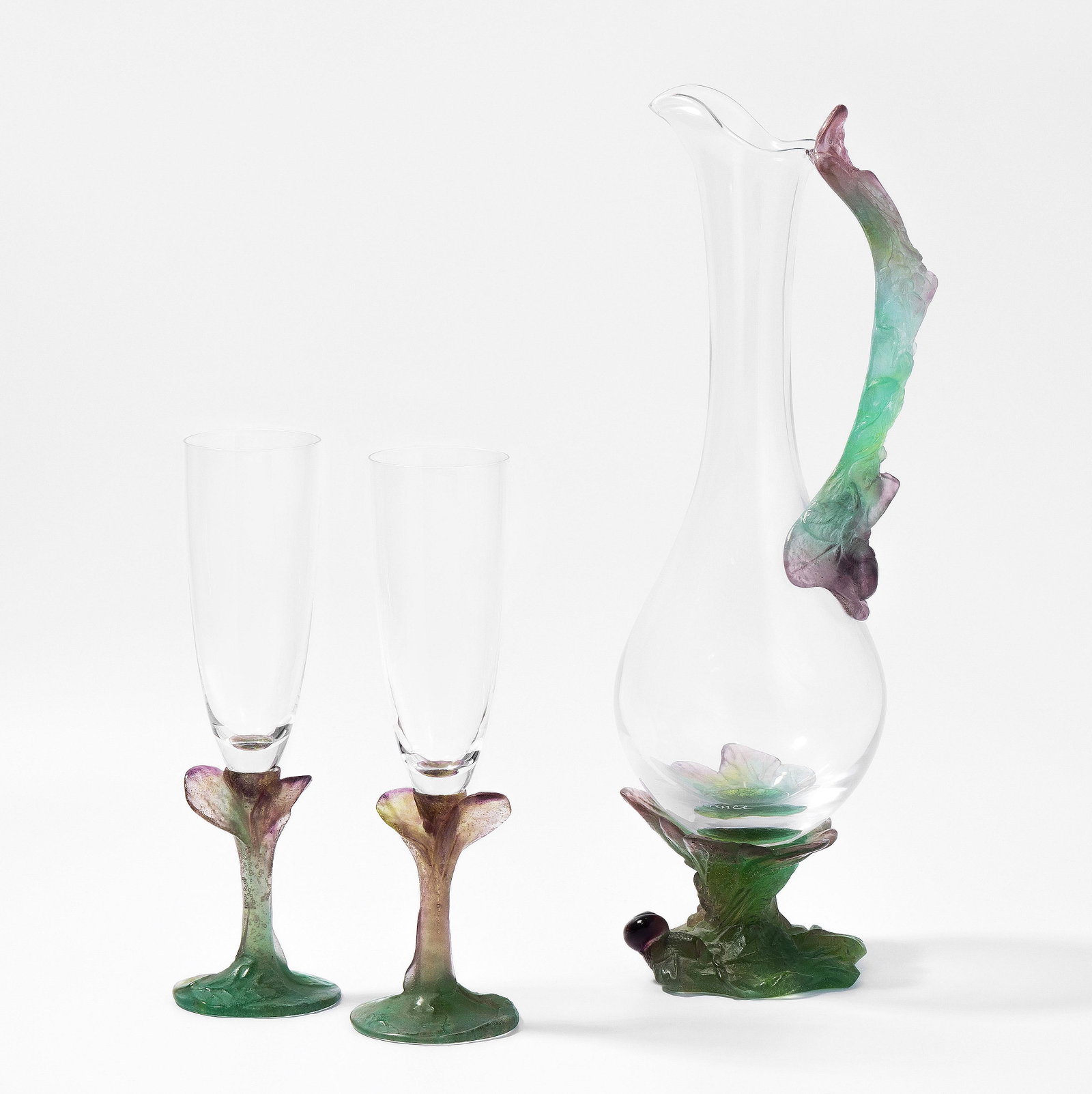 Karaffe und 2 Champagnergläser, Daum: Frankreich, 2. Hälfte 20.Jh. Farbloses Glas, grün-violettes Pâte-de-verre. Karaffe bezeichnet: Daum France. H (Karaffe) 38,5 cm; (Gläser) 24 cm.