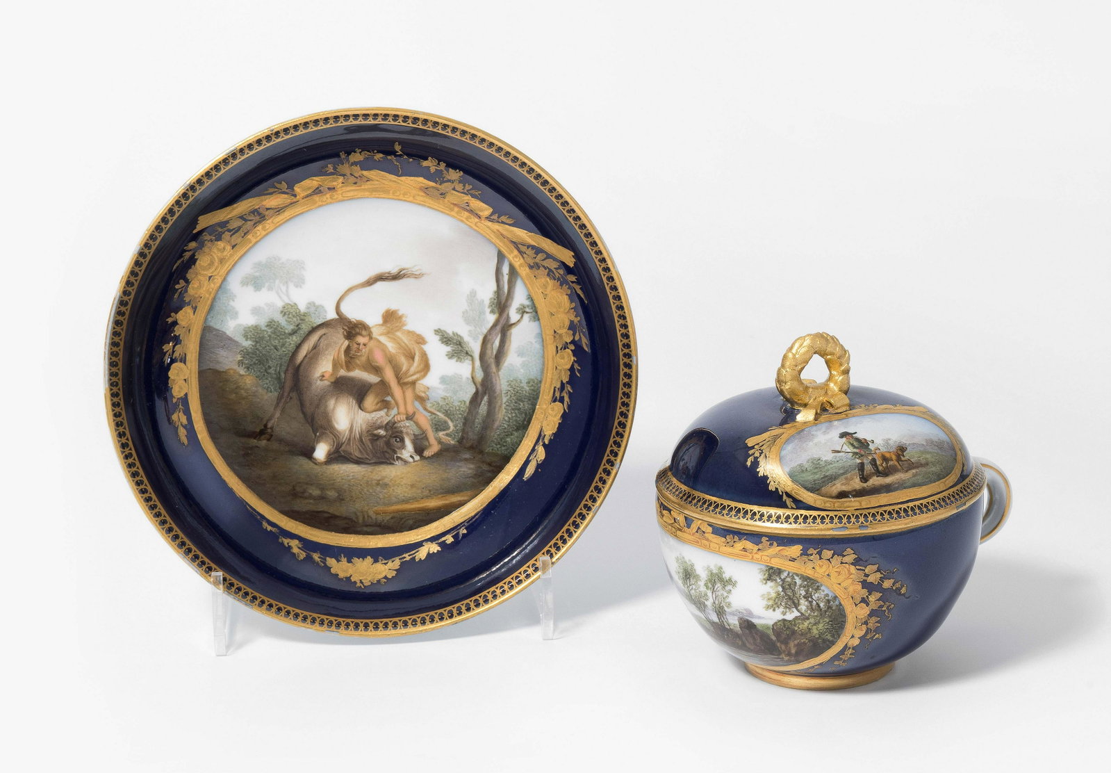 Meissen, Untertasse: Marcolini, 1774–1814. Unterglasurblaue Schwertermarke mit Stern, Presszahl 24, rote Malermarke 12. Polychrome Malerei in Reserve mit Blütenzweigen und Schleifen in mattem und poliertem Gold auf kö