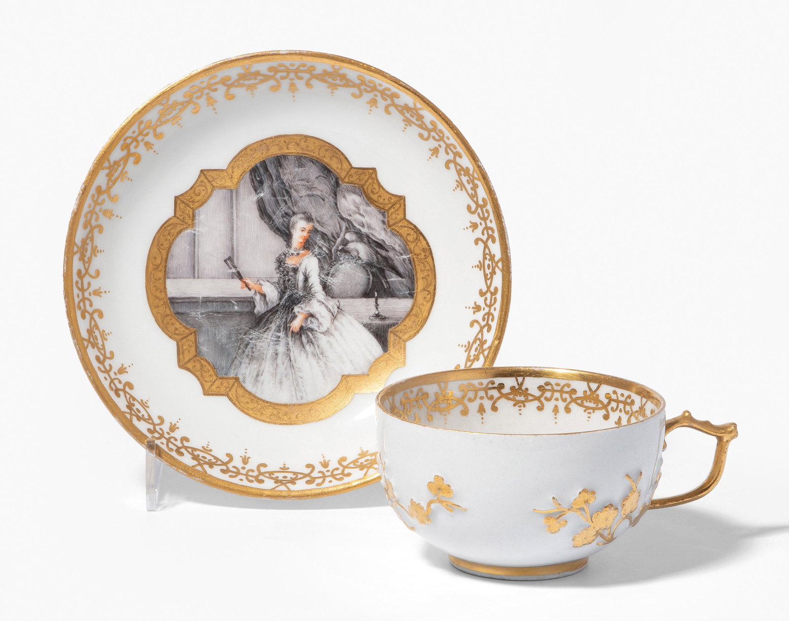Tasse mit Untertasse, Abraham Seuter: Meissen, um 1730. Porzellan. Unterglasurblaue Schwertermarke, Pressnummer 52 (Tasse). Die Wandungen aussen mit Prunusrelief. Hausmalerei von Abraham Seuter (1699–1747), Augsburg, um 1740. In Grisail