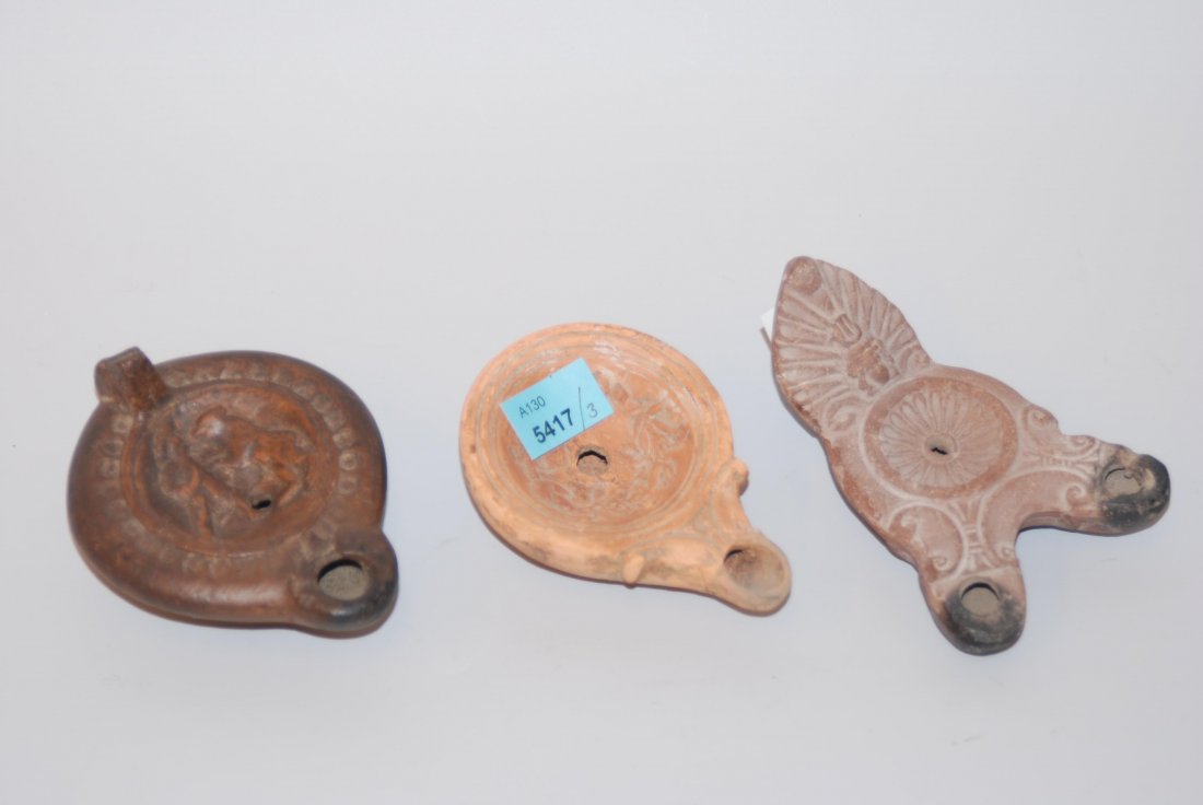 Lot von drei Öllampen Hellenistisch-römisch, 1.Jh. v.: Lot von drei Öllampen Hellenistisch-römisch, 1.Jh. v. Chr.–3.Jh n. Chr. Bräunlicher und orangeroter Ton. Griffllos mit Floraldekor. L 9 cm / Zapfengriff mit kl. Fülloch und Kampfszene zw. Mann u